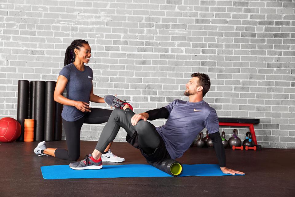 a fitness trainer teaching a client how to properly foam roll